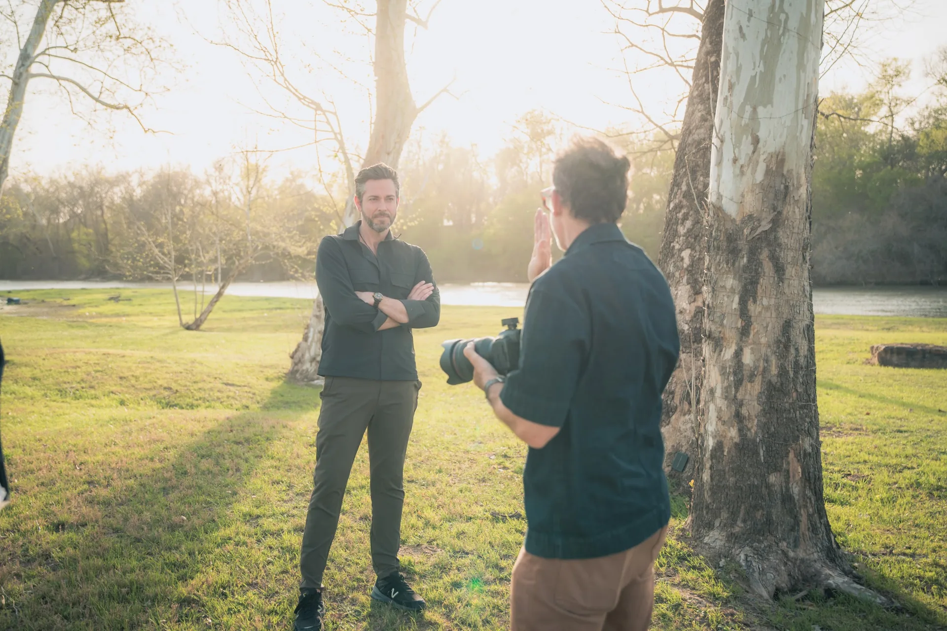 A camera operator filming in a field at golden hour